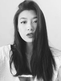 Portrait of beautiful young woman with black hair against wall