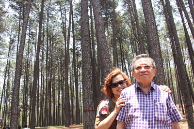 Happy woman with arms outstretched against trees in forest