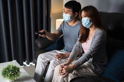 Young woman using mobile phone while sitting on sofa