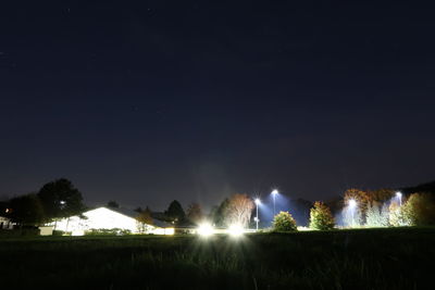 Illuminated field against sky at night