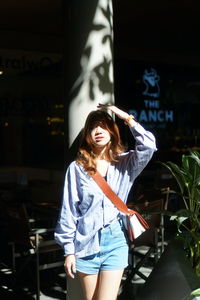 Portrait of young woman standing against wall
