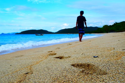 Rear view of man on beach against sky