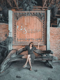 Portrait of woman sitting against brick wall