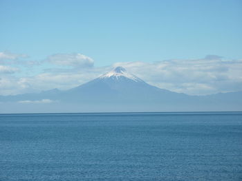 Scenic view of sea and mountains against blue sky