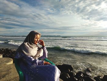 Woman looking at sea shore against sky