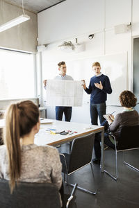 Young woman showing flipchart to friends and professor in classroom