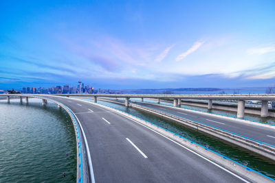 View of road by sea against blue sky