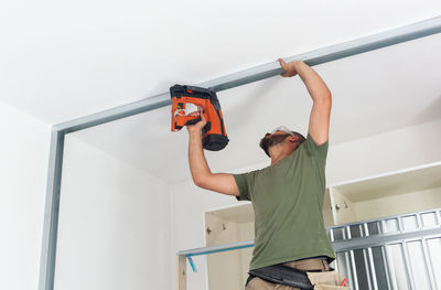 Low angle view of man working on wall at home