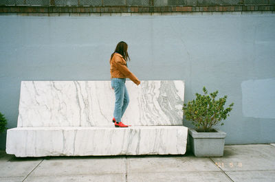 Rear view of woman on footpath against wall