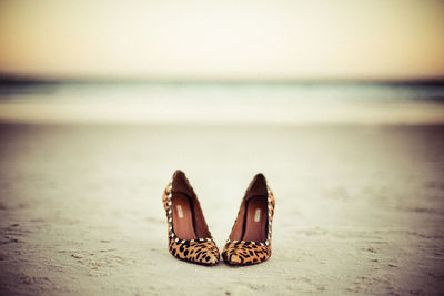 Close-up of shoes on beach