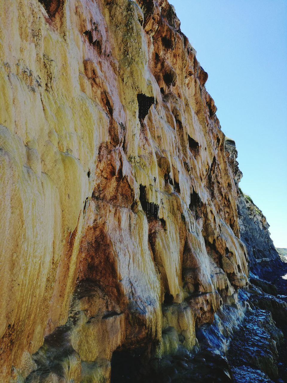 clear sky, low angle view, blue, scenics, tranquil scene, tranquility, nature, beauty in nature, rock formation, cliff, sky, physical geography, outdoors, geology, non-urban scene, day, mountain, rocky, eroded, no people, mountain range, green color