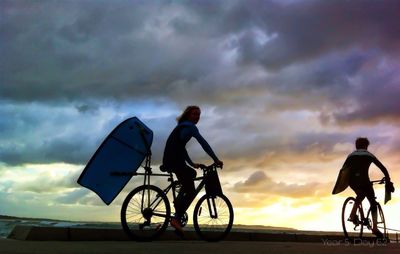People on road against cloudy sky during sunset