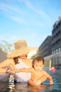 Portrait of shirtless boy in water against sky