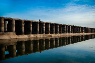 Bridge reflecting on lake against sky