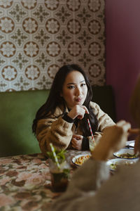 Young woman talking to friend during lunch at restaurant