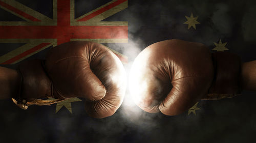 Cropped image of boxers fighting against illuminated australian flag