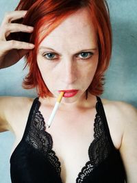 Close-up portrait of redhead woman smoking cigarette