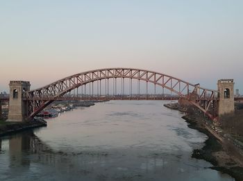 Bridge over river in city against clear sky