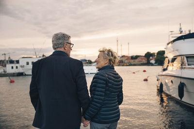 Rear view of senior man and woman communicating at harbor