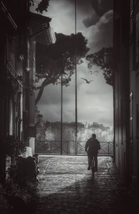 Rear view of silhouette person walking on street amidst buildings