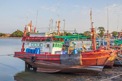Colorful fishing boats are securely tied down directly at the pier with seaman's ropes and knots