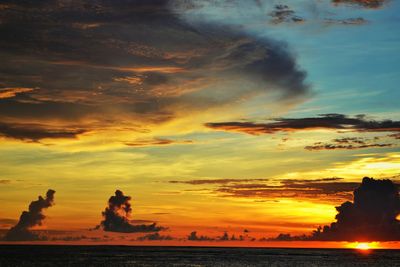 Scenic view of sea against dramatic sky during sunset