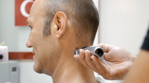 Barber trimming neck hair of mature man in salon