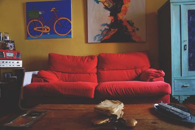 Empty sofa by papers and remote control on tables at home