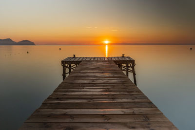 Pier over sea against sky during sunset