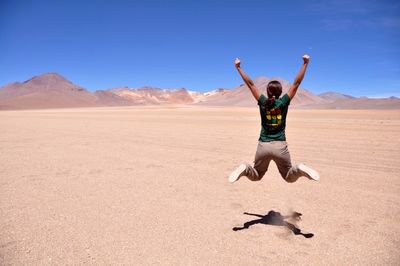 Full length of woman jumping against clear sky