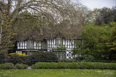 An old black and white building partly hidden by trees in peterborough, cambridgeshire, uk