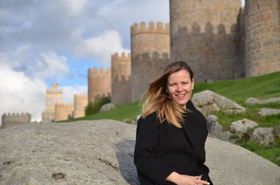 Portrait of smiling young woman standing against built structure