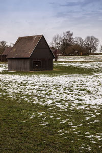 House on field by building against sky