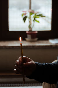 Cropped hand of person holding candle at home
