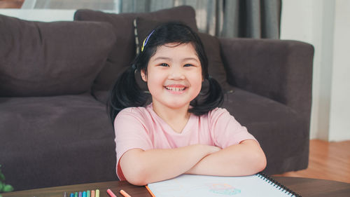 Portrait of a smiling girl sitting on sofa at home