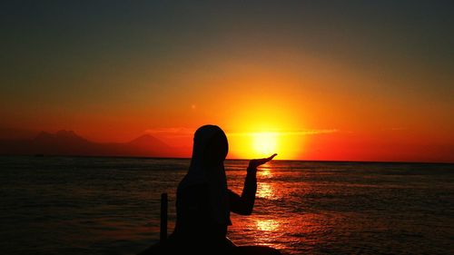 Silhouette person against sea during sunset