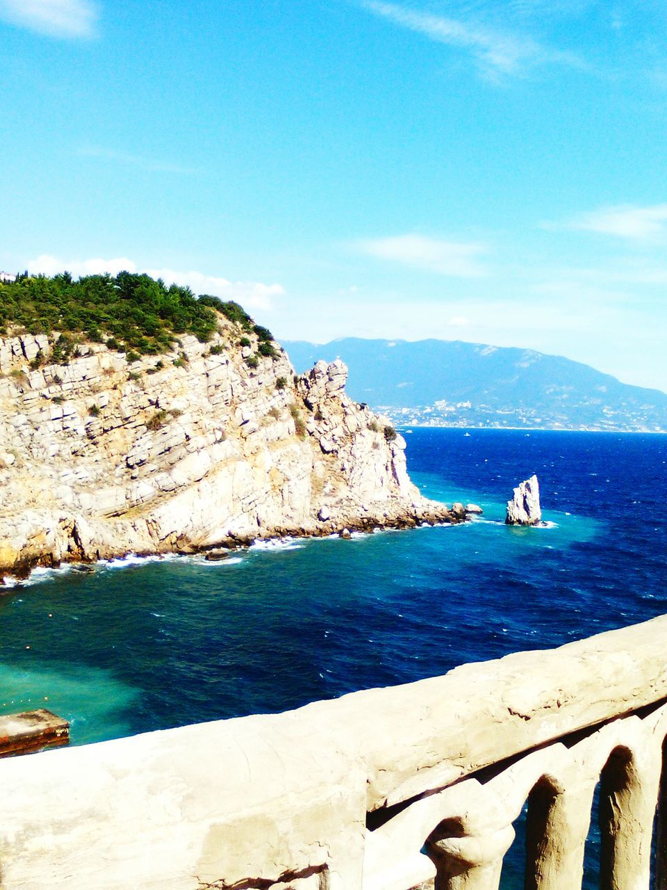 water, sea, mountain, sky, tranquil scene, scenics, beach, blue, tranquility, beauty in nature, cliff, nature, tourism, rock formation, shore, non-urban scene, vacations, outdoors, day, coastline, rocky mountains, cloud - sky, distant, remote, natural landmark