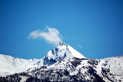 Low angle view of snowcapped mountains against blue sky