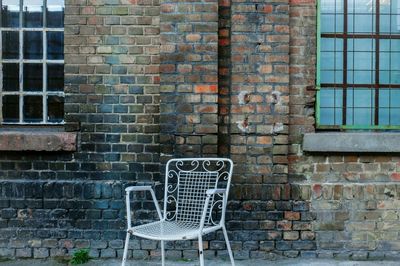 Empty chairs against brick wall