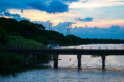 Bridge over river against sky during sunset