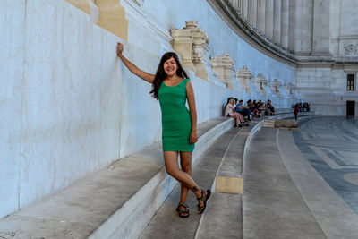 Full length portrait of woman standing against wall