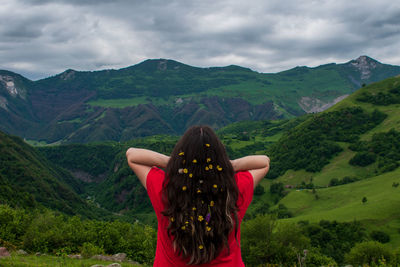 Rear view of woman standing on mountain against sky