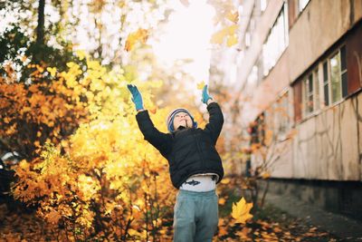 Cute boy throwing dry leaves during autumn