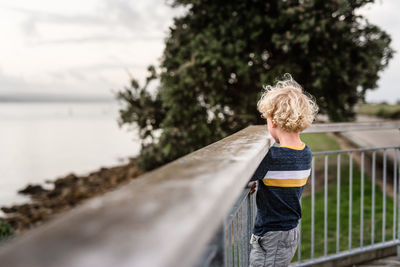Curly haired child looking over railing in napier, new zealand