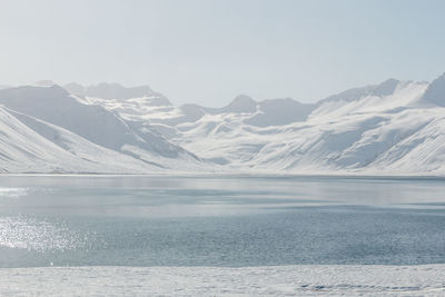 Scenic view of snowcapped mountains by sea against sky