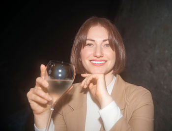 Cheerful lady enjoying a fine glass of wine in dim ambiance