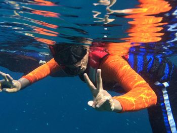 Portrait of young man gesturing peace sign while snorkeling in sea