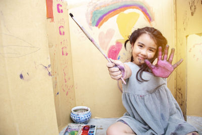 Portrait of happy girl sitting on wall