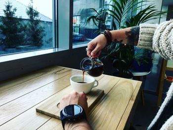 Man pouring coffee in cup on table