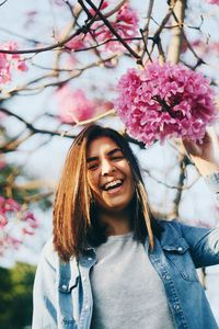 Portrait of happy young woman by pink flowers
